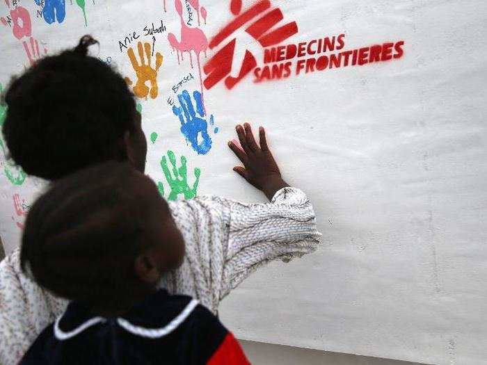 A mother and child put their handprints next to the prints of other survivors at a MSF clinic in Liberia.