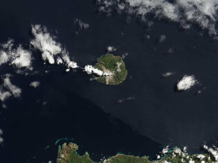 The Paluweh Volcano erupted in late 2012 and continued spewing material south of the summit months after the eruption. But in mid-2013 a smaller, second eruption deposited material to the north, killing five people.  You can see the brown material deposits both at south and north of the summit.