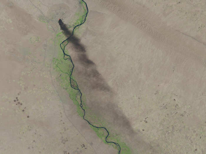 A black plume of smoke extends miles down from the largest oil refinery in Iraq, which was set on fire by insurgents who attacked the refinery earlier this year.