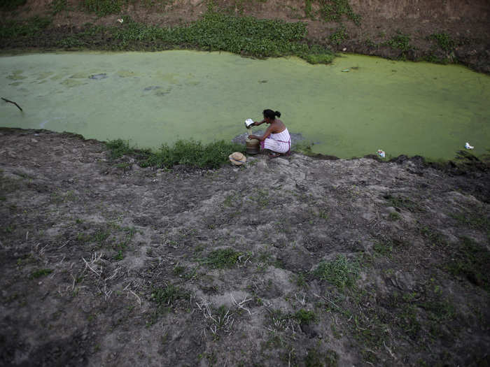 In 2012, floods ravaged parts of the Brazilian Amazon, while — in a twist of fate — droughts devastated the northeastern part of the country. Here, a woman scoops water from a nearly dried-up well in the country