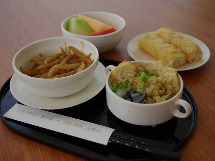 Enjoy a breakfast of fried short rice noodles with vegetables, preserved egg and pork porridge, Chinese doughnuts, and fresh fruit.