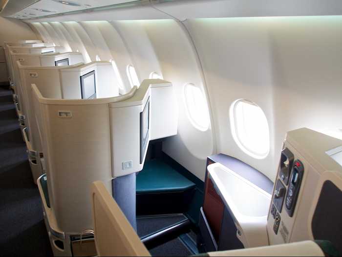 Every business class seat comes with ample leg room, a footrest, and a shelf to hold food and drinks.