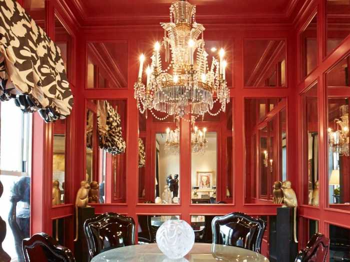 The dining room is intimate with an oversized window and Chinese Red French paneling with mercury glass on the walls.