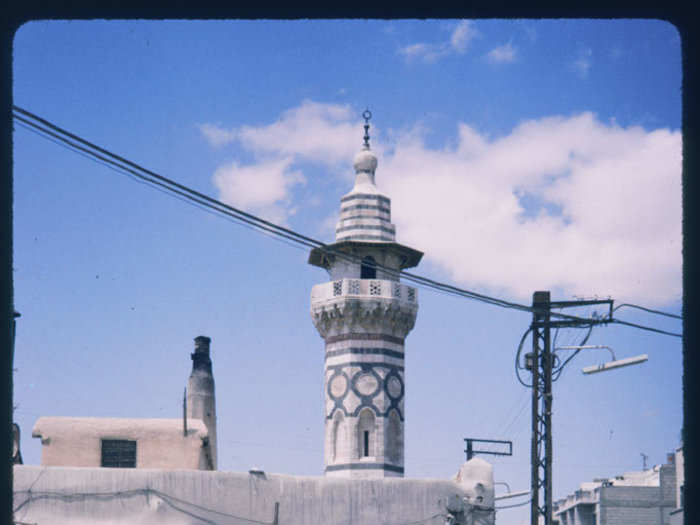 A minaret rises behind a busy market.