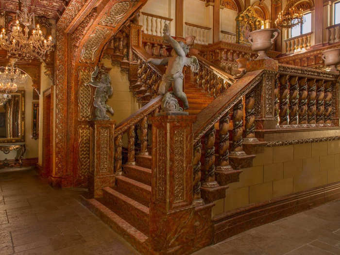 Custom design radiates throughout the entire home, like this custom-made carved wooden staircase with cherub statue designs.