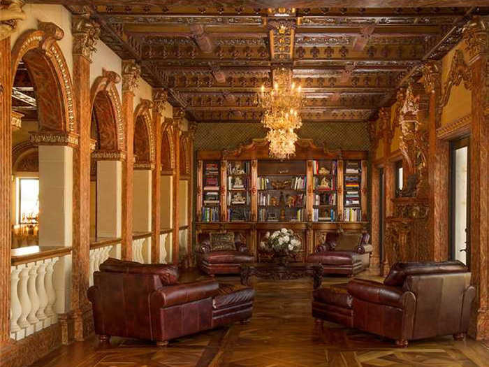 A library with a custom wooden bookcase overlooks the main living room.