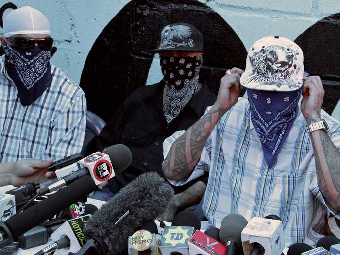 The situation grew so dire that the Catholic Church tried to broker a truce in May 2013 between gangs Calle 18 and Mara Salvatrucha. Below, masked members speak to the press with San Pedro Sula