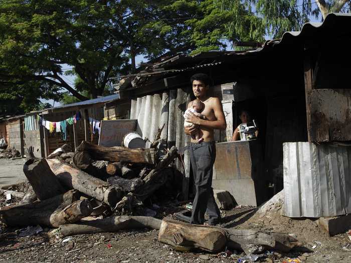 San Pedro Sulans live in both fear and poverty. In Honduras, the second poorest country in Latin America, 65% of the population lives below the poverty line. This man holds his baby outside their makeshift home in the "Rio Blanco" neighborhood of San Pedro Sula.