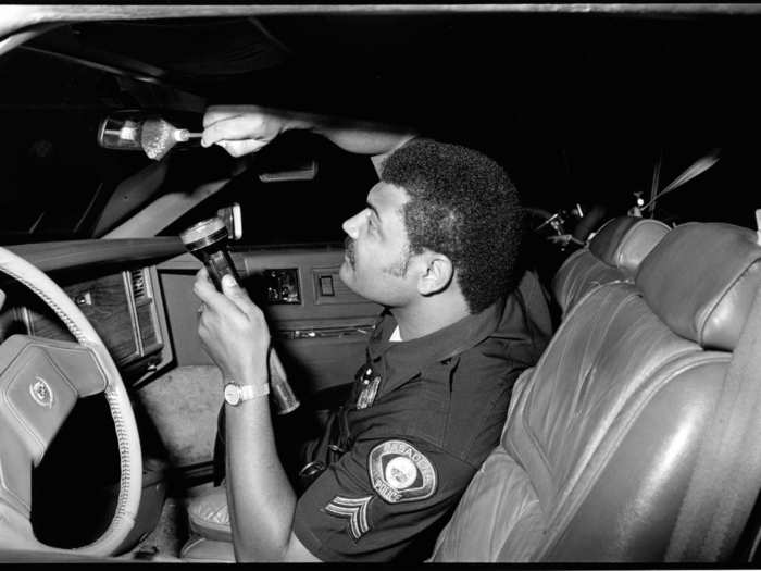 Agent Calvin Pratt dusts for fingerprints in a recovered stolen vehicle.