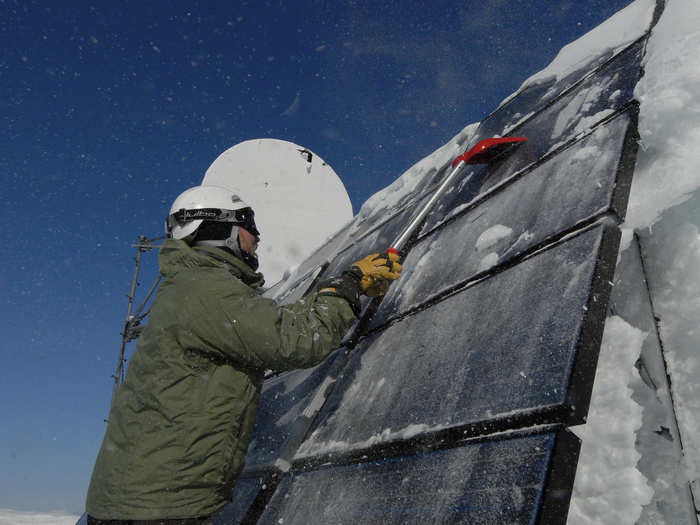 Keeping equipment in working order is difficult in Alaska, and a life-and-death issue for the Coast Guard. Here, a distress team leader clears ice and snow from solar panels that power a microwave link site for communications in western Alaska.