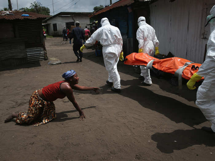 A woman crawled toward the body of her sister as an Ebola burial team took her for cremation in October. The burial of loved ones is important in Liberian culture, making cremation traumatic for surviving family members.