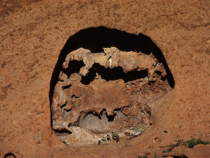 Smolan accompanied Davidson in her hike over Uluru, along with her four camels and her rescued dog, Diggity. Davidson had spent two years learning from Aboriginals to train camels and survive the desert. Here she is by a formation in the wall of Uluru.