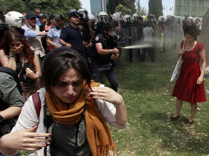 A Turkish riot policeman uses tear gas as people protest against the destruction of trees in a park brought about by a pedestrian project, in Taksim Square in central Istanbul in 2013.