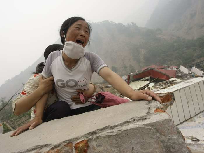 A woman cries as she cannot find her husband and 4-year-old daughter on the top of the ruins of a destroyed school in earthquake-hit Sichuan province of China on May 17, 2008.