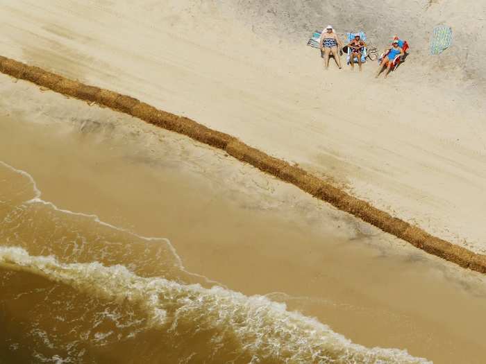 Beach goers sunbathe behind a wall of hay bales, used to absorb any oil that might come ashore, on Dauphin Island, Alabama in May of 2010.