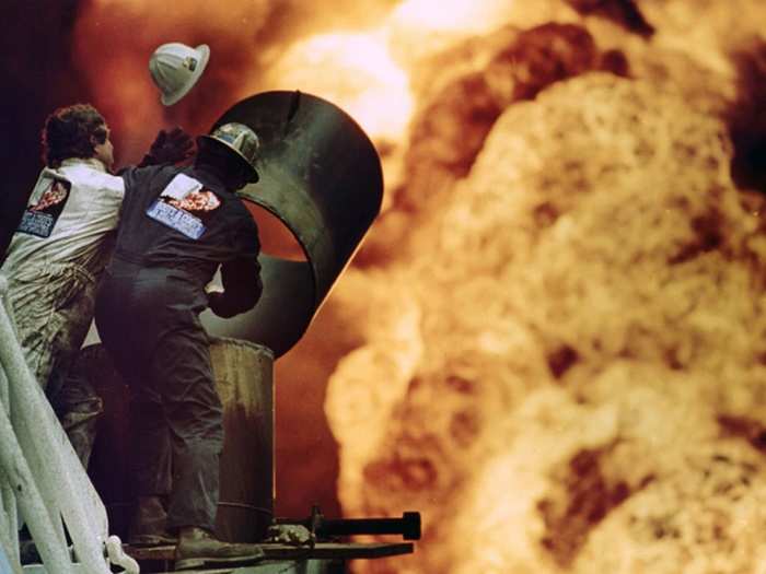 Oil fire fighters from Boots and Coots try to put out an oil well fire in Al-Ahmadi where retreating Saddam Hussein forces had set fire to the oil wells, in this March 30, 1991 photo.