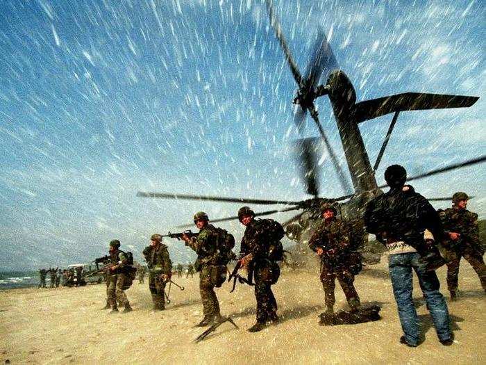 An Albanian man carries a child to a US Marine CH53 Super Stallion helicopter as it lands at Golame beach near the port of Durres, in this March 16, 1997 picture.