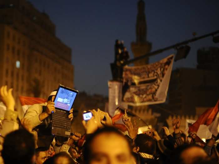 An opposition supporter holds up a laptop showing images of celebrations in Cairo