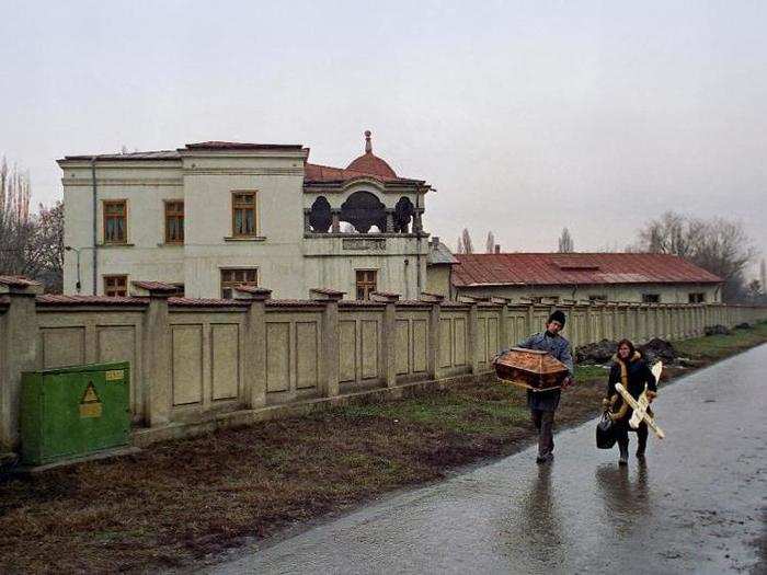 Romanian parents carry a small casket and cross as they arrive at a Bucharest hospital to collect the body of their dead baby who died of AIDS on February 6, 1990.