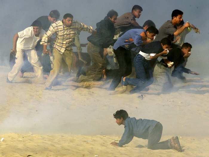 Palestinians try to run away from Israeli soldiers firing teargas during Palestinian-Israeli clashes in the southern Gaza Strip town of Khan Younis in October, 2000.