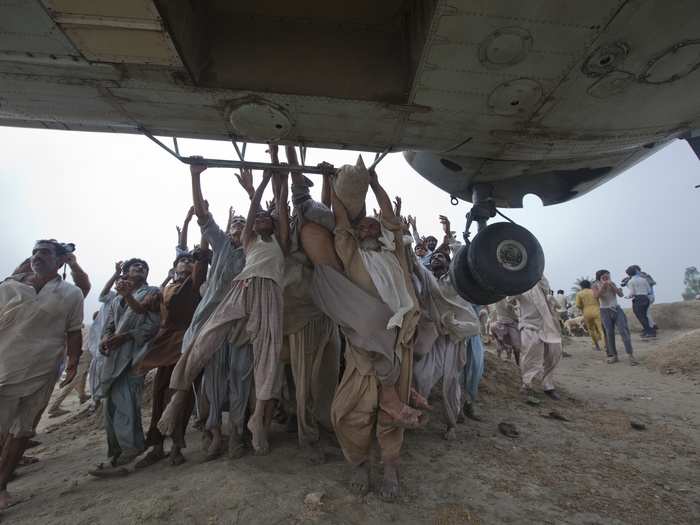 Marooned flood victims try to grab onto the side bars of a hovering army helicopter which arrived to distribute food supplies in the Muzaffargarh district of Pakistan