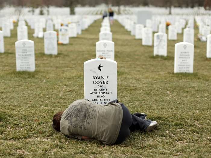 Lesleigh Coyer, 25, of Saginaw, Michigan, lies down in front of the grave of her brother, Ryan Coyer, who served with the U.S. Army in both Iraq and Afghanistan, at Arlington National Cemetery in Virginia in this photo from 2013. Coyer died of complications from an injury sustained in Afghanistan.