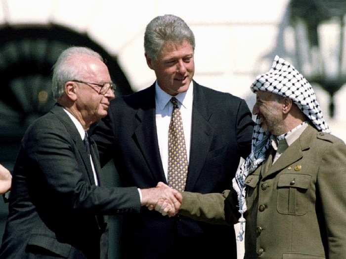 In this September 1993 photo, U.S. President Bill Clinton (C) looks on as Israeli Prime Minister Yitzhak Rabin (L) and Palestine Liberation Organization (PLO) leader Yasser Arafat shake hands after the signing of the Israeli-PLO peace accord at the White House.