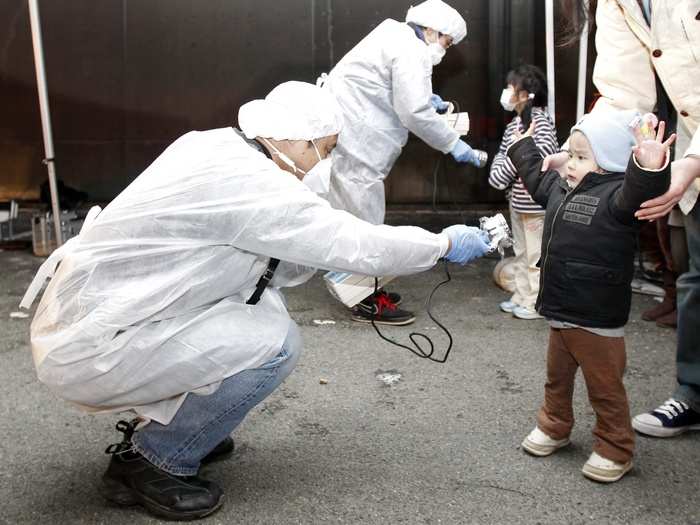 Officials in protective gear check for signs of radiation on children who are from the evacuation area near the Fukushima Daini nuclear plant in Koriyama on March 13, 2011. The biggest earthquake to hit Japan on record struck the northeast coast, triggering a 10-metre tsunami that swept away everything in its path, including houses, ships, cars and farm buildings on fire and caused the meltdown of the Fukushima nuclear power plant.