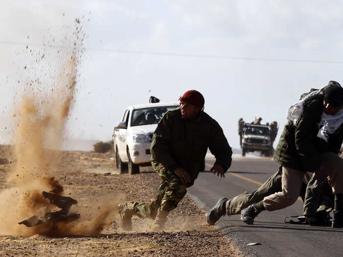 Rebel fighters jump away from shrapnel during heavy shelling by forces loyal to Libyan leader Muammar Gaddafi near Bin Jawad on March 6, 2011 file photo. Rebels in east Libya had regrouped and advanced on Bin Jawad after forces loyal to Muammar Gaddafi ambushed rebel fighters and ejected them from the town earlier in the day.