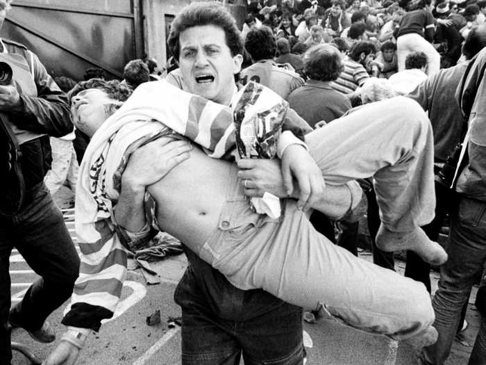 An injured soccer fan is carried to safety by a friend after a wall collapsed during violence between fans before the European Cup final between Juventus and Liverpool on May 29, 1985 at the Heysel stadium in Brussels. 39 people died, and a further 600 were injured.