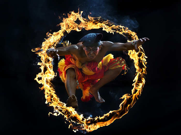 This photo was taken during the Bujang Ganong dance, a traditional attraction in Indonesia. The performer is jumping through a circle of fire.