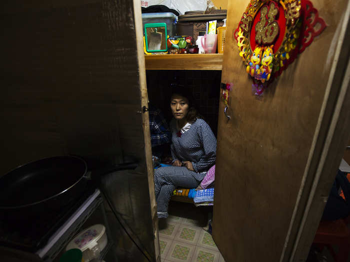 Li Rong, 37, sits on a bed in her 35-square-foot subdivided apartment, with just enough room for a bunk bed and small TV, on the fifth floor of an old industrial building in Hong Kong. Li and people like her live in some of the priciest real estate per square foot in the world.