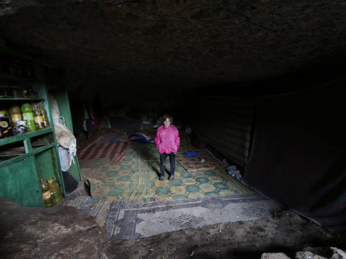 A displaced girl poses inside an underground cave in the southern countryside of Idlib on November 26, 2014. She