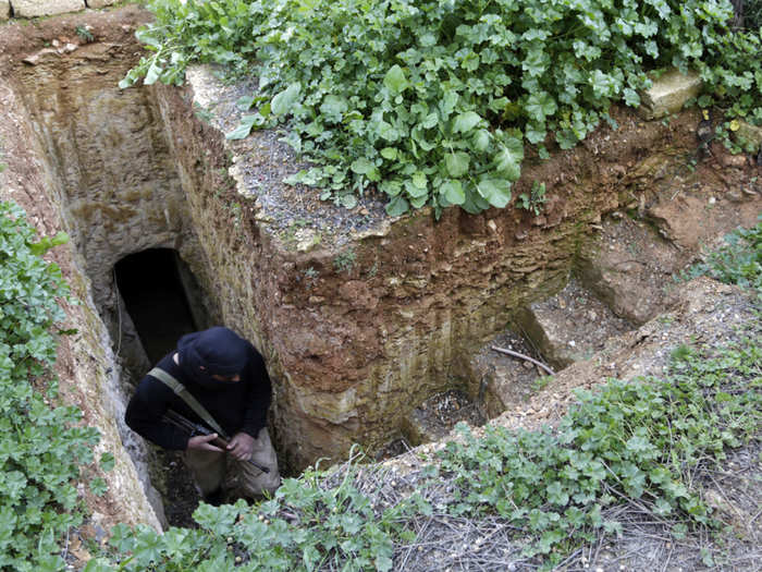 A rebel fighter of al-Badiya brigade in Jaysh al-Islam carries his weapon as he comes out from one of the caves used as shelter in al-Latamna town. The tunnels and caves created by the rebels can be very complex.