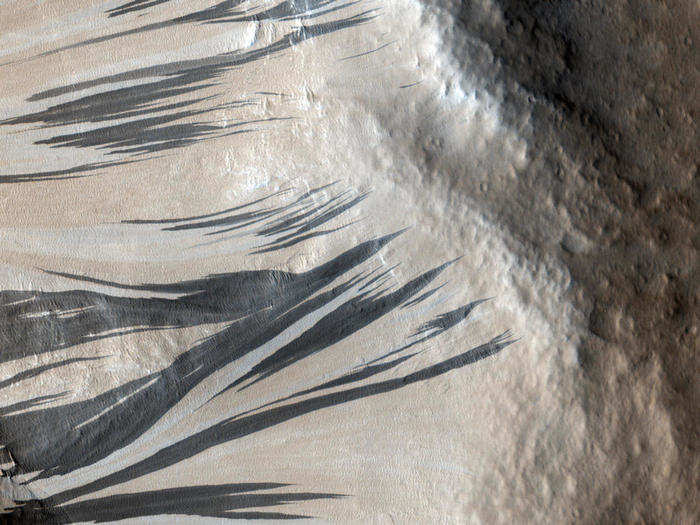 Dark and light streaks crawl up a ridge in this picture of the Acheron Fossae region. Scientists debate over how the different-colored streaks formed, but they agree that the darker streaks are younger that turn into the lighter streaks over time.