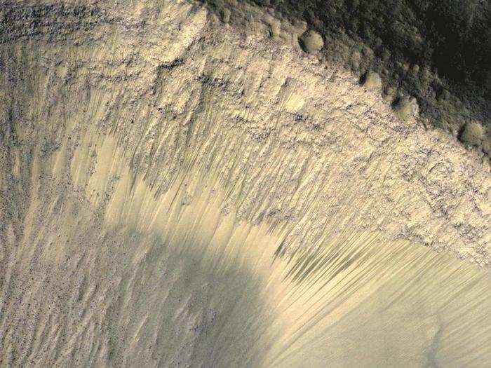 The steep slope of a crater, shown here, is located on the floor of Valles Marineris — a colossal canyon 2,500 miles long. The canyon is clearly visible from space, stretching across the Martian equator.