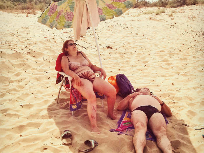 A couple relaxes under the hot sun on a beach in Sicily.