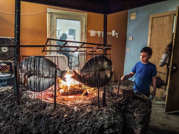 This young Iraqi boy helped his father grill buffalo fish, one of the most popular fish entrées in Iraq, over a fire pit.