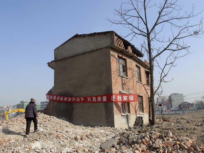 The banner on this nail house, which blocked the construction of new apartments in Hefei, Anhui province, in 2008, says, "strongly requesting the government to punish the developer who demolished my house, give back my home."