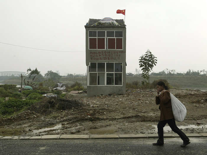 A woman walks past the last remaining home in an area on the outskirts of Nanjing in 2008. The owners had sought more money for their home from the developers of a wetland project.