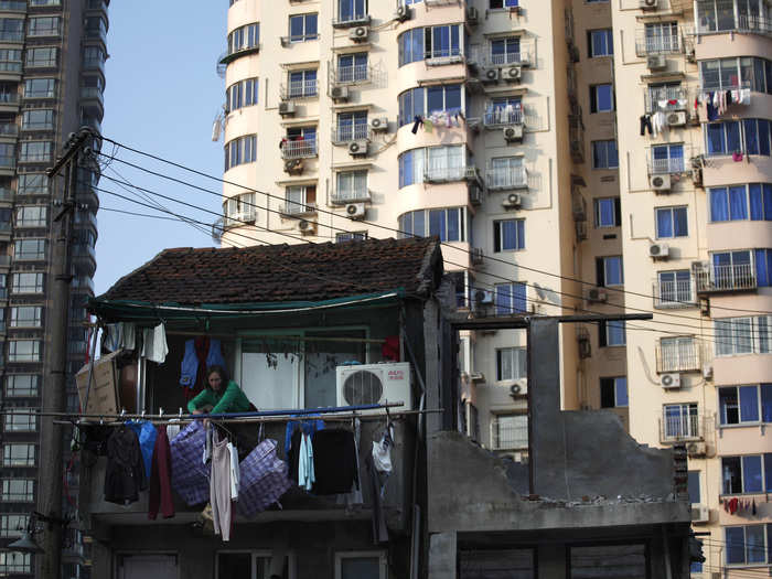 A woman stands on the balcony of her house, which was demolished to build new apartments in downtown Shanghai in December 2010.