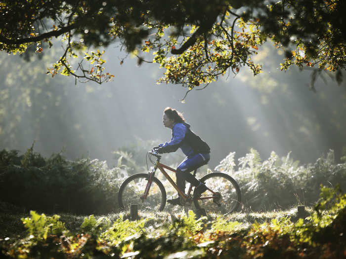 A woman cycles in the early-morning autumn sunshine in London