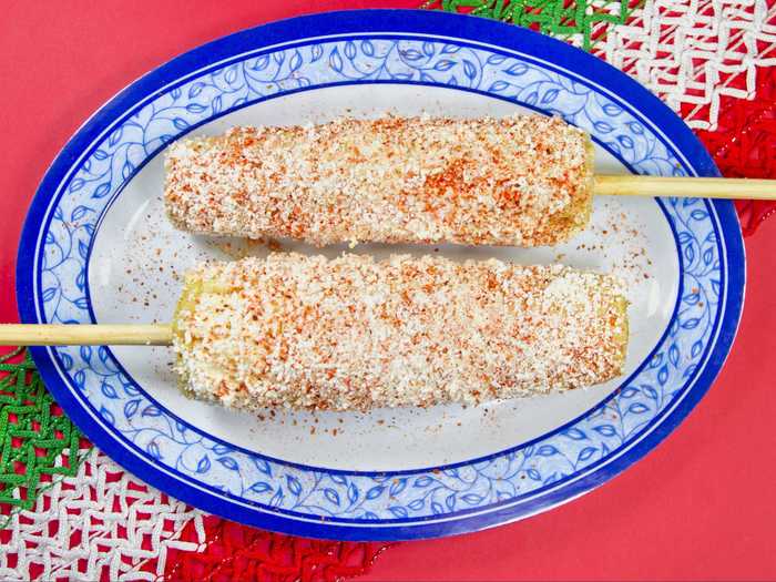 Elote (corn on the cob) is a common street food served both on a stick and in cups. The corn is boiled before being smothered in a delicious blend of salt, lime, chili powder, butter, cheese, and sour cream.