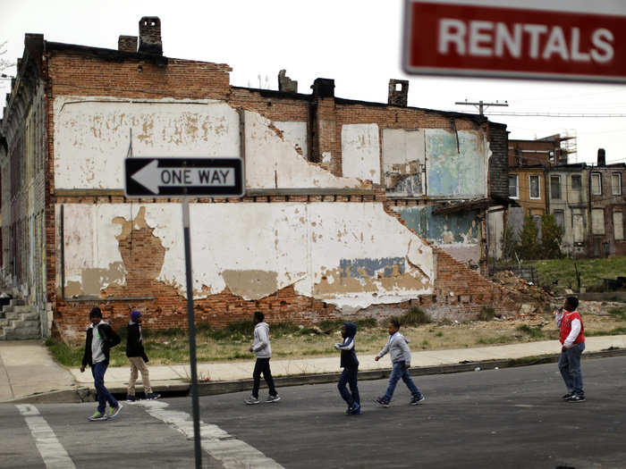 A group of boys walk past a partially collapsed row house in Baltimore. Today, an estimated 16,000 buildings in the city are vacant or abandoned.