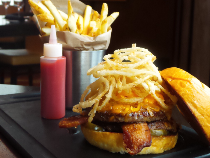 Atlanta, GA: The Prime BBQ Beef Burger is stacked tall with aged cheddar cheese, hickory smoked bacon, bread and butter pickles, and fried tobacco onions.