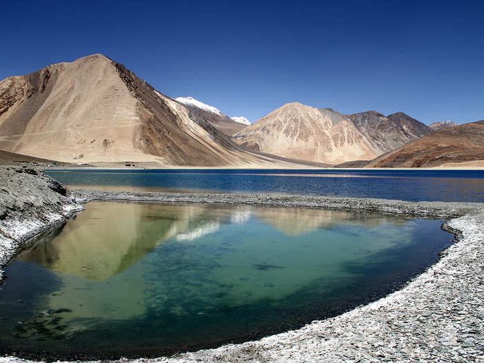 Nearly every picture of Pangong Tso — which is Tibetan for "long, narrow, enchanted lake" — makes the basin look like a piece of glass, reflecting the barren mountains behind it. It disects the Tibet-India border, and its clear waters allow visitors to see straight to the bottom.