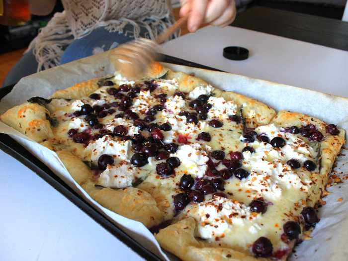 We were still waiting on two guests, but Michelle brought out the first pizza — a combination of cheddar and goat cheese, blueberries, red pepper flakes, and honey drizzled on top — so it could cool off.