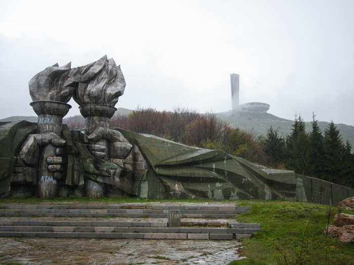 At the foot of the mountain stands a massive sculpture of two hands holding torches.