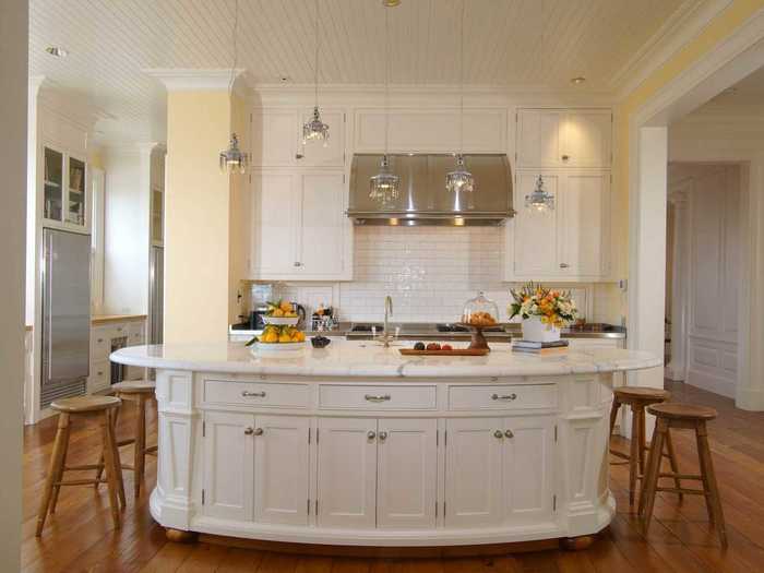 The kitchen has a large island and shiny light fixtures.