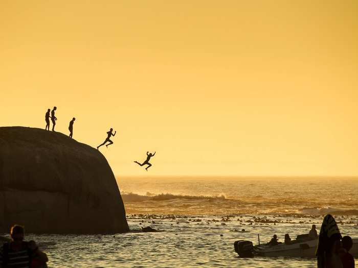 Boys jump into the Atlantic Ocean at Clifton Beach in Cape Town, South Africa.